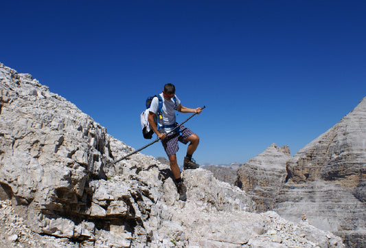 Ein Mann beim Abstieg von einem Berg-Grat nutzt den Mountrainer um sich abzustützen